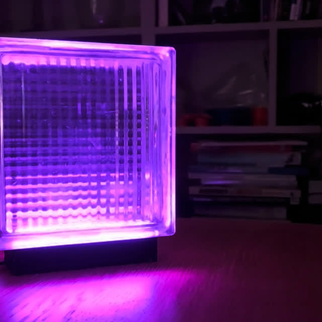 Purple lamp on a desk in front of a bookshelf